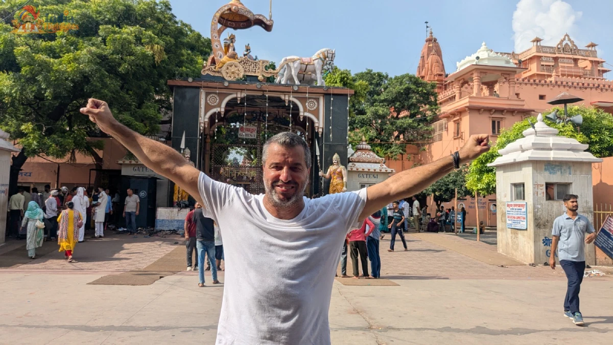 Enthusiastic traveler posing with outstretched arms outside Shri Krishna Janmabhoomi temple gate in Mathura