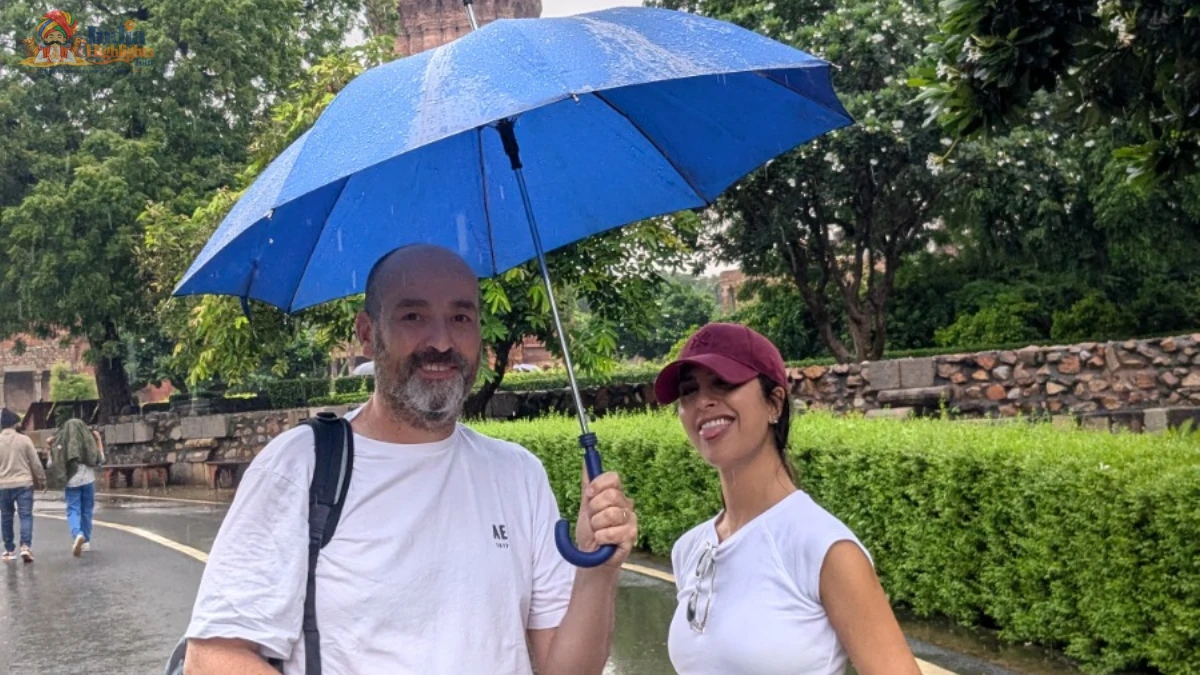 Couple enjoying a stroll under a blue umbrella on a rainy day at Qutub Minar complex in Delhi
