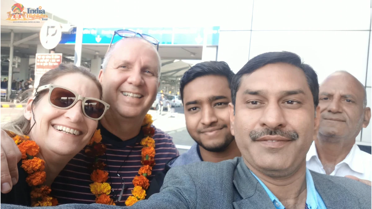 Joyful group selfie of tourists wearing flower garlands with India Highlights tour managers at airport arrival